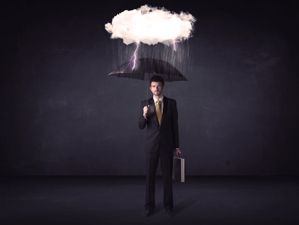 Businessman standing with umbrella and little storm cloud concept on background